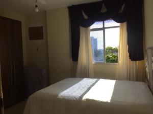 a bedroom with a bed and a window at Lindo e espacoso apartamento - Aracaju in Aracaju