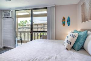 a bedroom with a bed with a view of a balcony at Kona Bali Kai 264 in Kailua-Kona