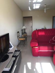 sala de estar con sofá rojo y TV en Lindo e espacoso apartamento - Aracaju, en Aracaju