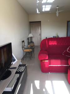 a living room with a red couch and a tv at Lindo e espacoso apartamento - Aracaju in Aracaju