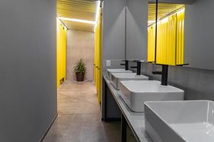 una fila di lavandini in un bagno con luci gialle di CHECK INN HOSTAL AEROPUERTO GDL a Guadalajara