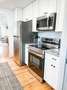 Una cocina con electrodomésticos de acero inoxidable y gabinetes blancos. en Changes In Latittude Retreat, en Daytona Beach