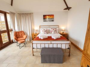 a bedroom with a bed and a chair at Barn Cottage in Alford