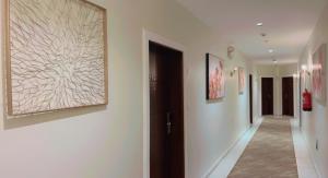吉達的住宿－Ghima Jeddah，走廊上设有白色的墙壁和墙上的绘画作品