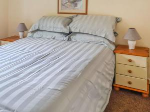 a bed in a bedroom with two night stands and two lamps at Craik Forestry Cottage in Teviothead