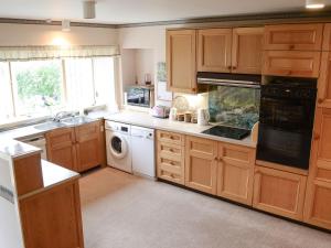 a kitchen with wooden cabinets and a sink and a dishwasher at Keith House in Thurso
