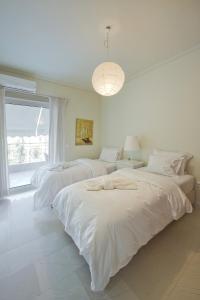 a white bedroom with two beds and a window at LucyZen in Athens