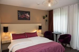 a bedroom with a large bed and two purple chairs at Serviced Apartments, Selbst-Check-in in Amtzell