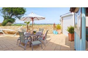 eine Terrasse mit Tisch, Stühlen und Sonnenschirm in der Unterkunft Pen Y Sarn in Abersoch