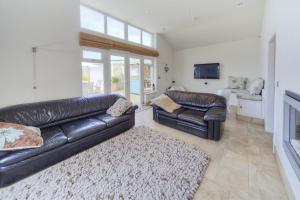 a living room with two leather couches and a television at Pen Y Sarn in Abersoch