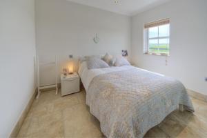a white bedroom with a bed and a window at Pen Y Sarn in Abersoch