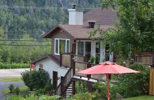 una casa con un paraguas rojo delante de ella en Chez Les Bergeron en Saint Aime Des Lacs