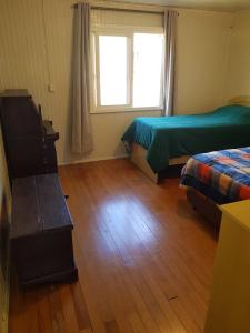 um quarto com 2 camas, uma janela e um piso de madeira em Casa Aurora em Cambará