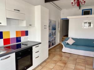 una cocina con armarios blancos y un sofá azul. en Studio Casa la fula, en Playa Quemada