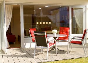 a patio with red chairs and a table on a porch at Haus Poseidon - Wohnung 1 1 in Wangerooge