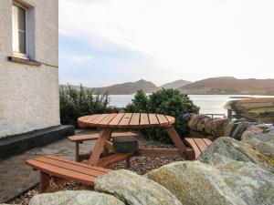 a wooden picnic table with a view of the water at Struthan in Valtos