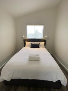 a bedroom with a large white bed with a window at Butmaroo Station in Bungendore