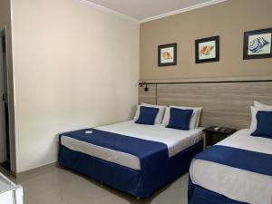 2 letti in una camera con blu e bianco di Summit Beach Hotel Boiçucanga a Boicucanga