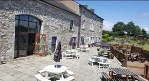 a patio with tables and umbrellas in front of a building at Carmels Caravan Borwick Lakes in Carnforth