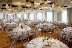 ロングビーチにあるアレグリア ホテルの白いテーブルと椅子、シャンデリアが備わる宴会場