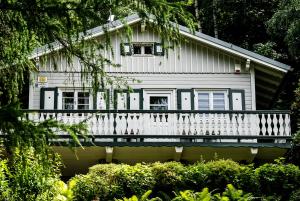 une maison blanche avec une véranda et des arbres dans l'établissement Willa Tyrolczyk, à Karpacz