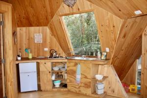eine Küche in einer Holzhütte mit einem Waschbecken und einem Fenster in der Unterkunft Lemunantu Domo Solar in La Ensenada