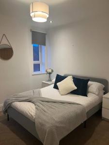 ein Schlafzimmer mit einem Bett mit blauen und weißen Kissen in der Unterkunft HU1 Hull City Centre Modern Apartment WIFI BATH H9 in Hull