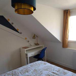 a bedroom with a bed and a desk and a blue chair at Appartement lumineux et moderne in Le Mans