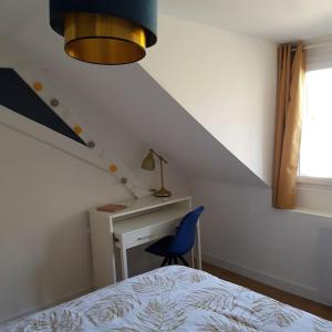 sypialnia z łóżkiem, biurkiem i niebieskim krzesłem w obiekcie Appartement lumineux et moderne w mieście Le Mans