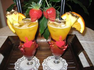 three cocktails on a table with strawberries and oranges at Drini Hotel in Durrës