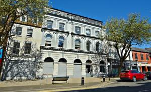 ein rotes Auto, das vor einem weißen Gebäude parkt in der Unterkunft HU1 Hull City Centre Modern Apartment WIFI BATH H9 in Hull