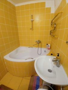 a yellow tiled bathroom with a tub and a sink at 4-км в центрі міста in Rivne