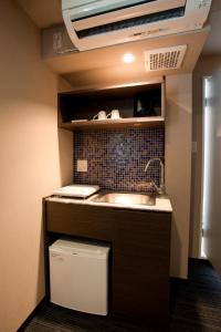 a small kitchen with a sink in a room at Kuretake Inn Premium Shizuoka Ekimae in Shizuoka