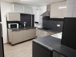 a kitchen with white cabinets and a black counter top at Le Wenalya avec terrain clôturé in Saint Die