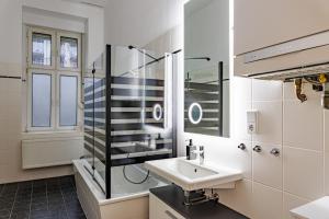 ein weißes Bad mit einem Waschbecken und einer Dusche in der Unterkunft DR Apartments Boxhagener Kiez in Berlin