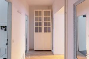 un corridoio con pareti bianche e una porta in vetro di DR Apartments Boxhagener Kiez a Berlino