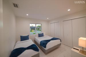 Duas camas num quarto branco com almofadas azuis em Miami Family Home 5BR Heated Pool & Jacuzzi L45 em Tamiami