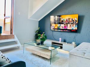 a living room with a glass coffee table and a tv at Homey 2-bedroom apartment & loft space in Sandton