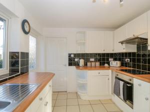 cocina con armarios blancos y encimera en 16 Dean Court, en Lydney