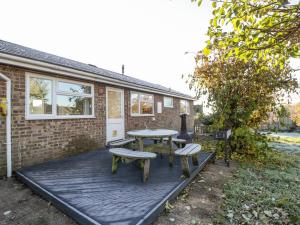 una terraza de madera con mesa y 2 bancos en 16 Dean Court, en Lydney