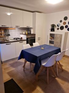 cocina con mesa azul y armarios blancos en Residenza L'Archetto, en Corona
