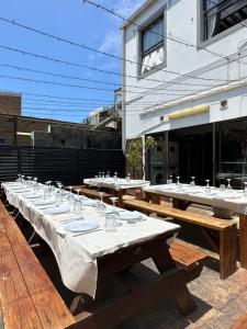 una fila de mesas de madera con copas de vino. en Bondi Beach Backpackers, en Sídney