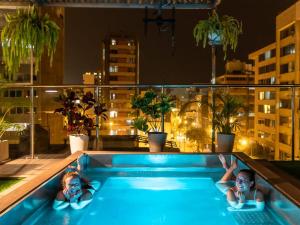 two people laying in a swimming pool on a balcony at night at Alpes Lima Kennedy Hostel in Lima
