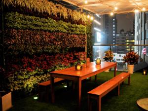 a table and benches in a room with a wall of flowers at Alpes Lima Kennedy Hostel in Lima