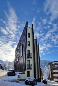 a building in the snow with cars parked around it at Randevu Nivalis in Jahorina