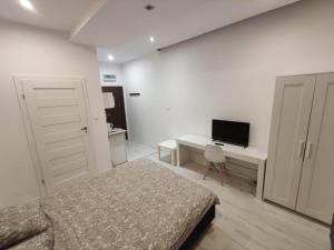 1 dormitorio con 1 cama y escritorio con TV en Micadas Apartamenty en Piaseczno
