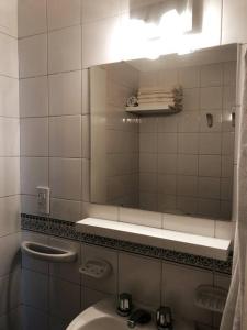 Baño de azulejos blancos con lavabo y espejo en Monoambiente céntrico en Tandil