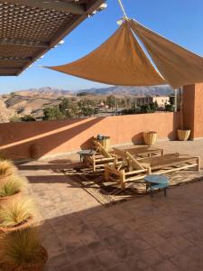 eine Terrasse mit Picknicktischen und einem großen Sonnenschirm in der Unterkunft Le Patio Du Lac in Lalla Takerkoust