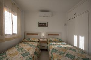 una piccola camera con due letti e un comodino di Holiday Beach Varadero a Santa Pola
