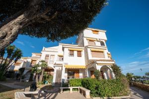 Uma casa branca com um banco à frente. em Holiday Beach Varadero em Santa Pola